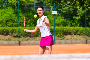 Woman playing tennis on court outdoors with racket in her hand